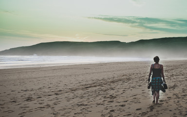 Naklejka premium woman walking on the beach at sunset