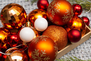 Christmas balls in a craft box on a gray background and with fir branches