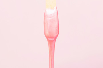 liquid wax for pink depilation drains from the stick. The concept of depilation, waxing, smooth...