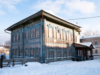 Fototapeta premium Russian old wooden two-storey house of pre-revolutionary construction, Sunny winter day.