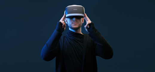 Model young man with beard in glasses of virtual reality on dark background. Augmented reality, future technology concept. VR. Free space for text.