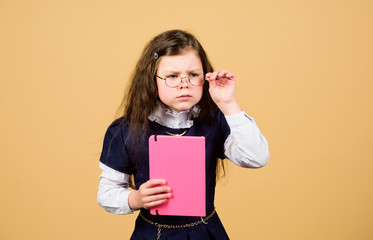serious small girl wants to be teacher. notebook for diary notes. study lesson. knowledge and education. Back to school. hometwork. small girl with paper folder. School curriculum