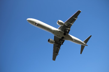 Flugzeug in der Luft mit ausgefahrenem Fahrwerk im Landeanflug und monochromer Hintergrund - Stockfoto