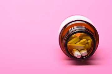 Closeup of a Prescription bottle of tablets with the cap off on a pink background with copy space.