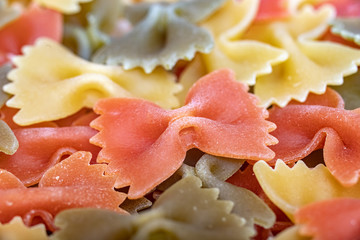 multicolored Italian raw Pasta Farfalle poured in large quantities. Background. Close up. tricolour.