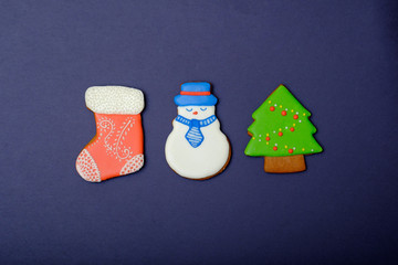 Background with decorative gingerbreads, cakes and Christmas tree sweets dessert. Holidays postcard with sweet cookies food. Sugar snowman, Christmas balls and fir tree.