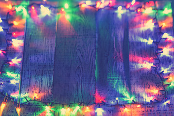Obraz na płótnie Canvas Wooden old table in festive red blue yellow green lights lights located at the edges of the photo. Frame of blurry bokeh lights with copy space on wooden background. Festive presentation table.