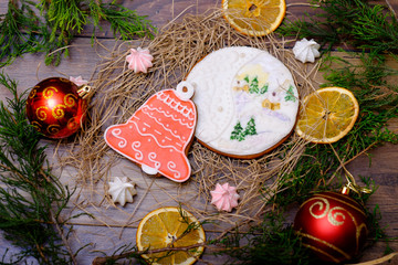 Wooden background with decorative gingerbread snowman cakes, Christmas tree branches, balls, oranges. Christmas postcard with sweets food, dessert.