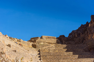 Inca archaeological site with the Sun Temple on the mountain at Ollantaytambo, Peru. Isolated on blue background.