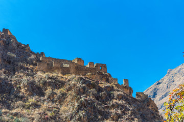 Inca archaeological site with the Sun Temple on the mountain at Ollantaytambo, Peru. Isolated on blue background.