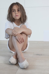 serious little girl seated on the floor