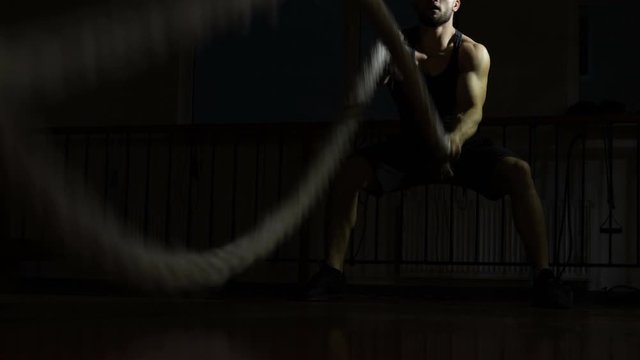 Man doing battle ropes workout, improving cardio and muscles, exhausted training
