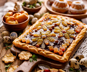Mazurek pastry, traditional Polish Easter cake made of shortcrust pastry,  chocolate cream, candied fruit, nuts and almonds on the holiday table, close-up. Very sweet dessert, Easter treat - obrazy, fototapety, plakaty