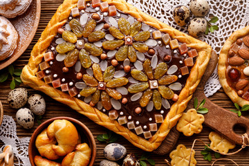 Mazurek pastry, traditional Polish Easter cake made of shortcrust pastry,  chocolate cream, candied fruit, nuts and almonds on the holiday table, top view, close-up. Very sweet dessert, Easter treat - obrazy, fototapety, plakaty