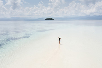 Woman walking alone on amazing tropical white sand beach. Aerial drone view from above. Tropical...
