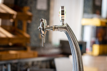 Close-up of shiny beer tap over unfocused background at brewery bar.
