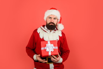 Serious man in Santa costume holds present gift box. Wish you merry Christmas. Santa Claus holds present. Santa with Christmas gift box. Merry Christmas and happy New year. New Year eve. Present box.