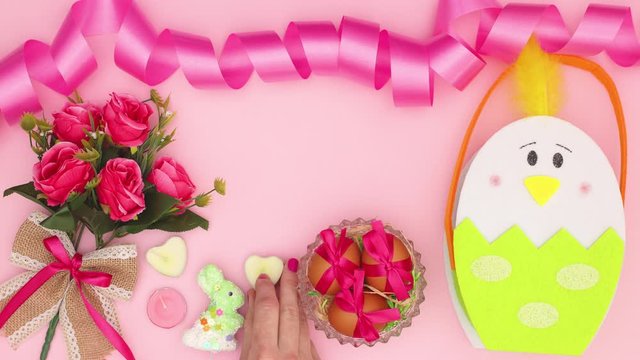 Woman's hand put Easter decoration on pink background - Stop motion 