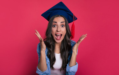 Eager student. Close-up photo of an excited student in a blue shirt and a square academic hat, who is screaming and gesticulating with her palms opened, as a sign of extreme happiness.