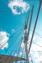 Fototapeta premium Ship mast of frigate, longboat or navy battleship. Metal mast pole. Lowered sails, blue sky on background.