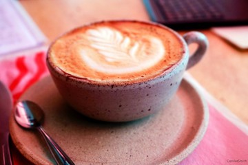 cup of coffee with cream on wooden background