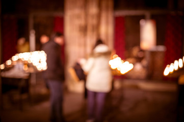 Defocused silhouettes of people in front of lighten candles in Notre-Dame de Strasbourg cathedral