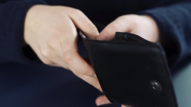 Woman hands open empty black leather wallet without money inside. Close up slow motion of empty wallet in woman hands. 4K.