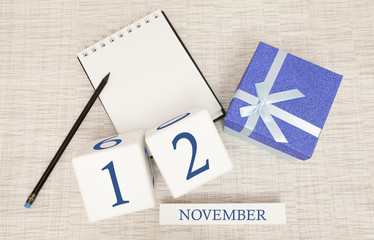Notepad and wooden calendar for November 12, next to a blue gift box.