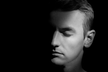 Fototapeta premium black and white dramatic portrait of a guy close-up on a black background with one light source