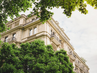 View through green trees of dream parisian apartment building real estate in France haussmannian architecture - obrazy, fototapety, plakaty