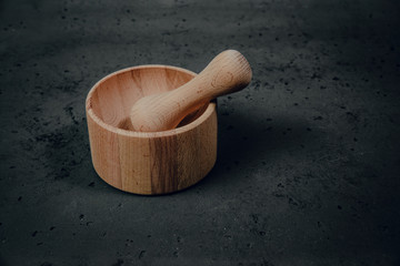 Wooden mortar with herbs on stone background. The concept of crushing and crushing spices, herbs. Preparation of ointments, creams. Caring for health, natural methods of obtaining medicines.