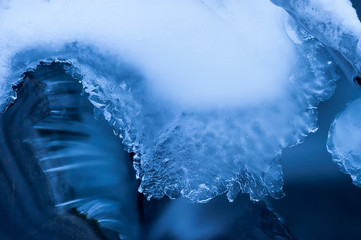 Ice on a blurred stream. Winter abstraction. Blue and white background. Water and ice.