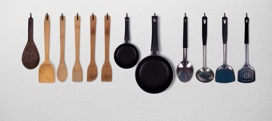 Set of kitchen utensils hanging on white wall background.stainless steel...