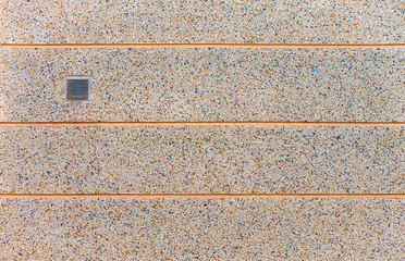 An empty warm creamy wall surface with horizontal lines and a vent cover.