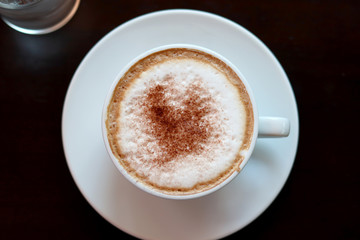 Cappuccino or latte with frothy foam, coffee cup top view closeup.