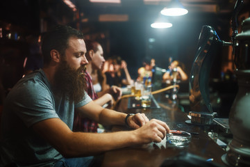 solemn bearded man smoking cigarette in bar