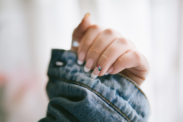 Elegant and long lasting woman french manicure with colorful beads and denim jacket. Lady hand with french manicure. Beauty female nails. Femininity and Beauty concept