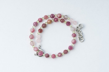 Handmade bracelet made of pink tourmaline, green chalcedony on a white background