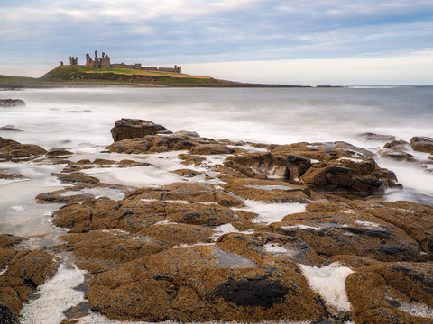 The stunningly rugged coastline of Holy Island in Northumberland is protected by Lindisfarne Castle on a beautiful winters morning.