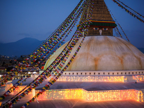 Buddhist shrine Boudhanath Stupa with pray flags over sunset sky. Nepal, Kathmandu