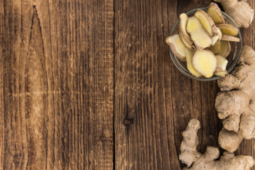 Some Ginger Slices on a vintage wooden table (selective focus; close-up shot)