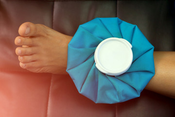 Women compress ice bag  to the ankle, relieving pain.on green background.