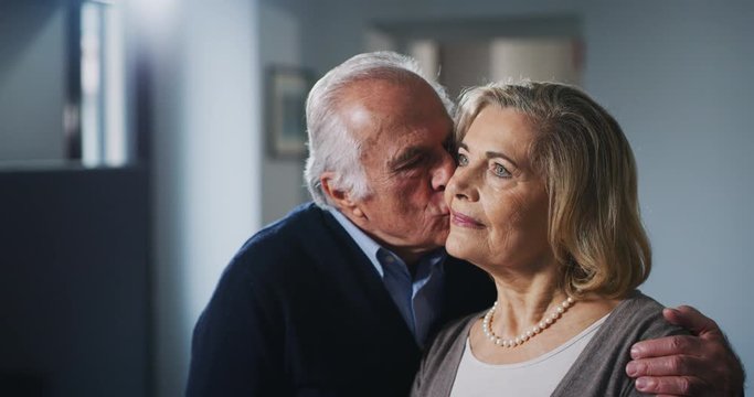 Close up of a lovely senior husband is giving a kiss to his wife as a sign of forever love at home.