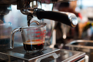 Coffee in measuring cup on a coffee machine