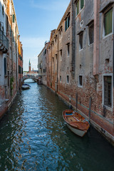 Boat in Narrow Canal in Venice with Campanile in Background