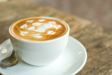 cup of coffee with cream on wooden background