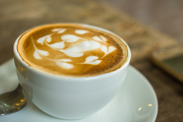 cup of coffee with cream on wooden background