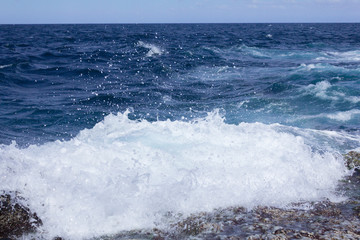 Blue atlantic ocean, white foam and volcanic rock