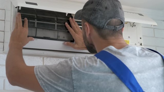 Air conditioning service. A man is repairing a household air conditioner.