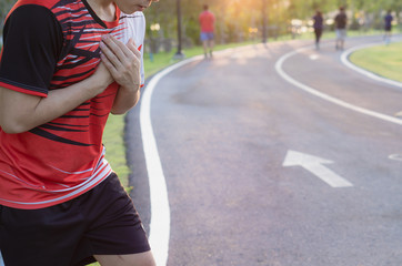 Sport man having heart attack or chest pain after running workout at park. Sport and Health care concept.